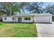 Landscaped front yard of a charming white home with a gray roof and a two-car garage at 303 Suzette Dr, Brandon, FL 33511