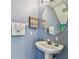 Cozy powder room featuring a pedestal sink, round mirror, and beach-themed decor, creating a relaxing atmosphere at 11162 Kapok Grand Cir, Madeira Beach, FL 33708