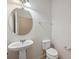 Bright powder room featuring a pedestal sink, round mirror, and modern toilet at 11544 Brighton Knoll Loop, Riverview, FL 33579