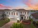Charming two-story home featuring a brick driveway, two-car garage, and manicured landscaping at sunset at 11544 Brighton Knoll Loop, Riverview, FL 33579
