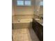 Relaxing bathroom featuring a soaking tub, granite countertop vanity, and neutral tile flooring at 11648 Palmetto Pine St, Riverview, FL 33569