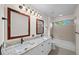 Bathroom with double sinks, granite countertops, wood-framed mirrors, a tub and updated fixtures at 11815 Marblehead Dr, Tampa, FL 33626