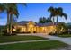 Stunning home exterior featuring lush landscaping, mature palm trees, and a well-manicured lawn at dusk at 11815 Marblehead Dr, Tampa, FL 33626
