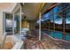 Stylish patio with brick flooring, outdoor furniture, and access to a screened-in pool; living areas visible through windows at 11815 Marblehead Dr, Tampa, FL 33626