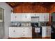 Bright kitchen features wood-paneled ceilings, white cabinets, black appliances, and a tiled backsplash at 12651 Tinley Rd, New Port Richey, FL 34654