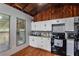 Bright kitchen features wood-paneled ceilings, white cabinets, black appliances, and a tiled backsplash at 12651 Tinley Rd, New Port Richey, FL 34654