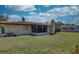 Exterior view of the home with a spacious backyard featuring a red tiled roof and a screened-in porch at 1450 Highfield Dr, Clearwater, FL 33764