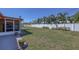 Large backyard showcasing a lush lawn and a privacy fence, framed by palm trees and a blue sky at 1450 Highfield Dr, Clearwater, FL 33764