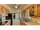 Bright kitchen featuring wood cabinets, neutral tile, black appliances, and a view towards the dining area at 1450 Highfield Dr, Clearwater, FL 33764
