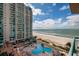 Aerial view of condo building featuring a pool, palm trees, and waterfront views at 1520 Gulf Blvd # 805, Clearwater Beach, FL 33767