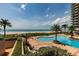 Community pool with beautiful beach and ocean views surrounded by palm trees and lounge chairs at 1520 Gulf Blvd # 805, Clearwater Beach, FL 33767