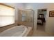 Bright bathroom featuring a soaking tub with a shower and a view into the main bedroom at 1648 Mira Lago Cir, Ruskin, FL 33570