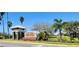 A welcoming Mira Lago community entrance with stone accents, lush landscaping, and swaying palm trees at 1648 Mira Lago Cir, Ruskin, FL 33570