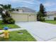Three-car garage with large driveway on a well-maintained lawn at 1648 Mira Lago Cir, Ruskin, FL 33570