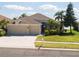 Charming front of home with a three-car garage, manicured lawn, and tropical trees at 1648 Mira Lago Cir, Ruskin, FL 33570