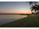 Picturesque lake view at sunset featuring calm waters, lush green shoreline, and distant residential skyline at 1648 Mira Lago Cir, Ruskin, FL 33570