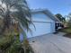 Attached two-car garage in a light-blue home with mature landscaping and a white garage door at 1982 Seton Dr, Clearwater, FL 33763