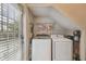 Compact laundry room with modern washer and dryer, storage shelves, and a window at 2807 W Estrella St # 102, Tampa, FL 33629