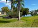 Peaceful backyard featuring a pond view, lush green grass, and mature trees at 284 Hemingway Dr, Oldsmar, FL 34677