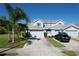 Two-story home featuring a light blue exterior, gray roof, blue shutters, and a spacious driveway with two cars parked at 284 Hemingway Dr, Oldsmar, FL 34677