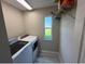Functional laundry room with updated washer and dryer, storage shelf, and a window at 284 Hemingway Dr, Oldsmar, FL 34677
