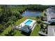Aerial view of a community pool and a pond bordered by lush trees and well-manicured lawns at 284 Hemingway Dr, Oldsmar, FL 34677