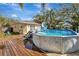 Above-ground backyard pool with a deck, slide, ladder, wooden perimeter deck and yellow house at 4716 Gazania St, New Port Richey, FL 34652