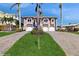 Beige home featuring dual garages, staircase, and tropical landscaping at 750 123Rd Ave, Treasure Island, FL 33706
