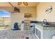 Outdoor kitchen with a grill, sink, bar area and stone countertop at 750 123Rd Ave, Treasure Island, FL 33706