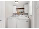 Efficient laundry room featuring a white washer and dryer, upper cabinets, and a rustic open shelf at 8517 43Rd W Ave, Bradenton, FL 34209