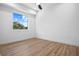 Bedroom with laminate wood flooring, baseboard trim, fan, and a large window overlooking trees at 870 N Osceola Ave, Clearwater, FL 33755