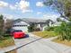 Well-maintained home features a lush front yard, a red sports car, and an attached two-car garage at 915 Brittany Park Blvd, Tarpon Springs, FL 34689