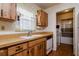 Functional kitchen with wood cabinets, white sink, and view to laundry room at 9170 Dupont Ave, Spring Hill, FL 34608