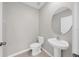 Modern half bath features a pedestal sink, round mirror, and neutral color palette at 9505 Lemon Drop Loop, Ruskin, FL 33573