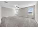 Spacious bedroom with plush gray carpeting, ceiling fan, and plenty of natural light from three windows at 9505 Lemon Drop Loop, Ruskin, FL 33573
