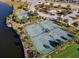 Aerial view of tennis courts and basketball courts surrounded by green spaces and lush landscaping near a waterway at 9505 Lemon Drop Loop, Ruskin, FL 33573