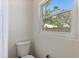 Bathroom with a toilet and a window, showing backyard trees at 9862 48Th N Ave, St Petersburg, FL 33708