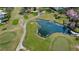 Aerial view showcasing a pond amidst green fairways on an active golf course community at 1022 Mctavish Way, Palm Harbor, FL 34684