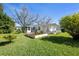 Spacious backyard showcasing a garden, a screen porch, lush greenery, and the home's exterior under a clear sky at 1022 Mctavish Way, Palm Harbor, FL 34684