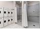 Clean shower room with gray tiled walls, white shower curtains, and individual lockers at 14191 Heritage Landing Boulevard # 1234, Punta Gorda, FL 33955
