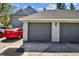 A two car garage with gray doors attached to a light blue home with a red car parked nearby at 2515 S Ysabella Ave, Tampa, FL 33629
