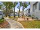Outdoor patio area with a stone bench, chairs, brick fire pit, and lush green landscaping and foliage at 2515 S Ysabella Ave, Tampa, FL 33629