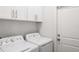 Laundry room with white washer, dryer, cabinets, and a door at 4104 E Comanche Ave, Tampa, FL 33610