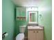 Bright half bathroom with light green walls, decorative mirror and white vanity at 500 Treasure Island Cswy # 402, Treasure Island, FL 33706