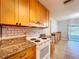 Well-lit kitchen with granite counters, wood cabinetry, white appliances, and a tile backsplash at 808 Smith Bay Dr, Brandon, FL 33510