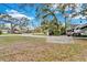 Front yard with grass, mature trees, and a wide driveway at 9811 Memorial Hwy, Tampa, FL 33615