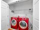 Well-lit laundry room includes red front loading machines, shelving, and white walls at 9811 Memorial Hwy, Tampa, FL 33615