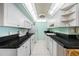 Bright kitchen features white cabinetry, black countertops, and updated appliances under a unique light fixture at 10355 Paradise Blvd # 614, Treasure Island, FL 33706
