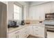 Close up on the kitchen featuring white countertops and cabinets, tile backsplash, and stainless appliances at 188 Brightwater Dr # 2, Clearwater Beach, FL 33767