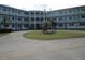 Low-angle exterior of a condominium building with a circle driveway, lawn, and U.S. flag at 1950 59Th N Ave # 212, St Petersburg, FL 33714